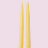 Two yellow candles on a light pink background