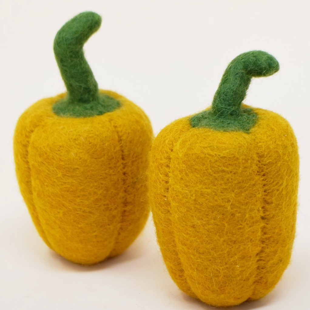 Two yellow felted peppers with green stems on a white background