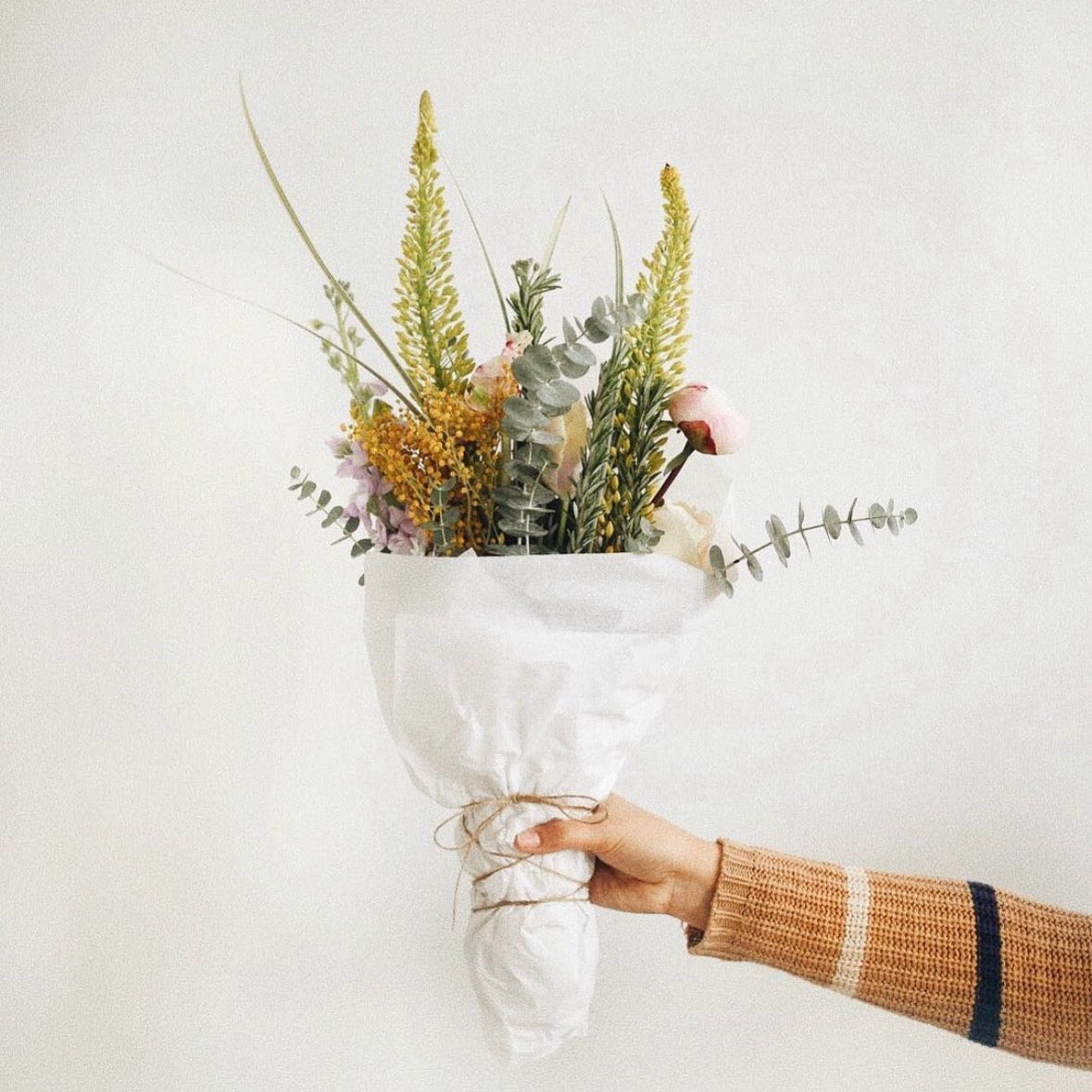 Bouquet of flowers held by a person against a white background